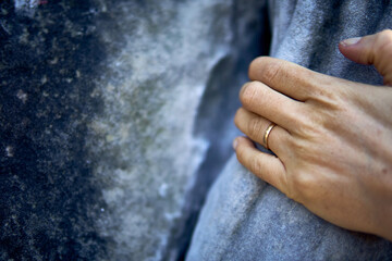 Close-up of a hand gently touching a textured stone surface during a warm afternoon in a peaceful outdoor setting