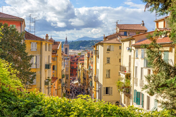 Nice, France. Upside view to the crowded narrow street in the old town, mountains in the background.