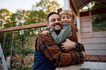 Fototapeta premium Happy father and daughter embracing with eyes closed on playground in autumn.