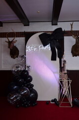photo zone with a large black bow and transparent balloons
