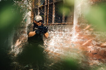 Obraz premium Soldier aiming with assault rifle near abandoned building