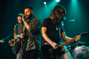 Rock band performing live on stage with singer and guitarist