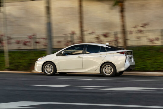 White Toyota Prius in movement, Panning shot of hybrid sedan in city street, High Resolution