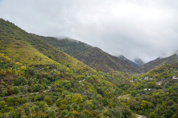 Fototapeta premium Scenic view of lush green mountains enveloped by clouds, showcasing the beauty of untouched nature. The serene landscape invites a feeling of tranquility and peacefulness. Autumn in Armenia