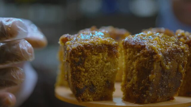 Gloved hand placing slices of cake onto a display tower close up
