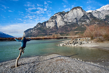 Exploring a tranquil mountain lake with a child balancing on a tree branch near the shore