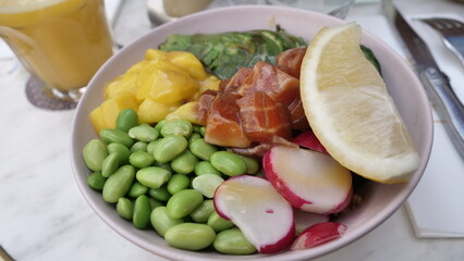 Poke bowl for balanced dietl with tuna, avocado, mango, cucumber, lettuce and rice, soy sauce and sesame seeds.