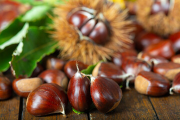 Chestnuts with leaves and burs on a wooden table