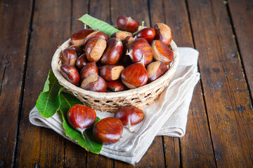 Chestnuts with leaves and burs on a wooden table
