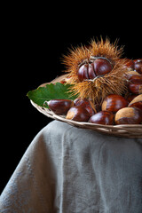 Chestnuts with leaves and burs on a wooden table