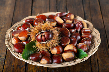 Chestnuts with leaves and burs on a wooden table