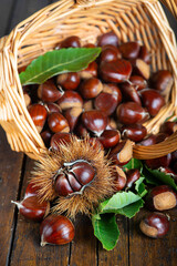 Chestnuts with leaves and burs on a wooden table