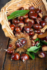 Chestnuts with leaves and burs on a wooden table