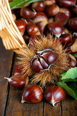 Chestnuts with leaves and burs on a wooden table