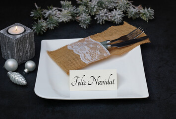 Feliz Navidad: Mesa con platos, cubiertos, adornos navideños y una tarjeta con la inscripción...