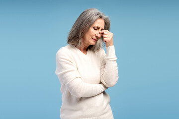 Portrait of sick, tired mature, gray haired woman having headaches, with closed eyes