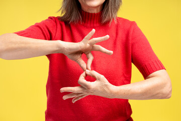 Portrait of senior woman wearing stylish red sweater, gesturing, showing symbols with fingers
