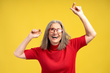 Portrait smiling senior woman wearing stylish eyeglasses and red sweater dancing
