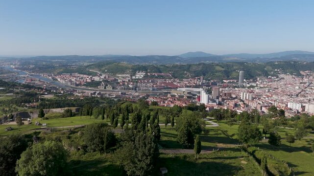 Drone footage of the green Mount Cobetas overlooking Bilbao city on a sunny day in Biscay, Spain