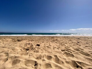 Serene sandy beach under a clear blue sky.