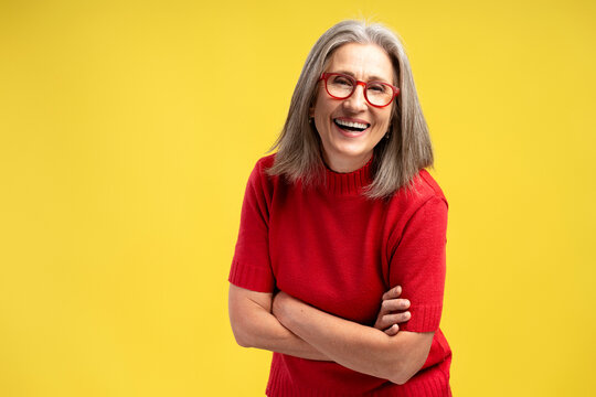 Beautiful, smiling senior woman wearing stylish eyeglasses and red sweater with crossed arms - Powered by Adobe