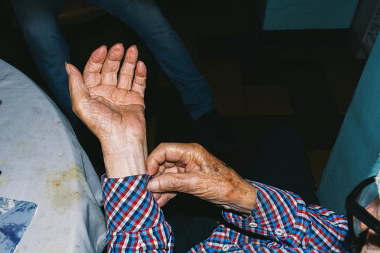 Elderly man&rsquo;s wrinkled hands adjusting shirt 