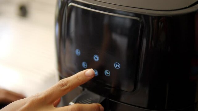 Close up to one hand of a woman programming an air fryer to cook food without oil, healthy cooking