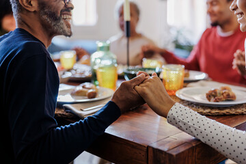 Happy family holding hands and praying before thanksgiving dinner