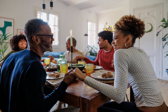 Happy family holding hands and praying before christmas lunch