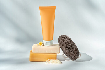 Modern still life with cosmetic tube, soap, flowers and pumice stone.