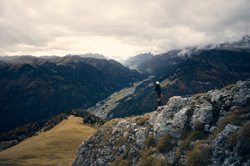 Mountain climber enjoying the breathtaking view from a rocky peak in the Alps during autumn