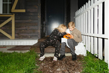 Children inspecting Halloween candy on a porch

