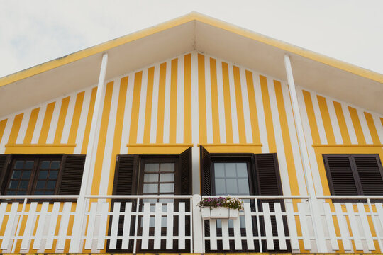 A charming house with yellow and white vertical stripes on its facade