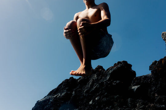 Anonymous teenager taking an extreme dive from the top of a cliff