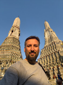 A man is standing in front of two tall buildings