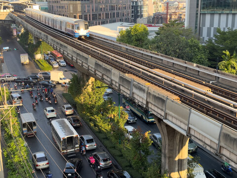 A busy city street with a train crossing over it