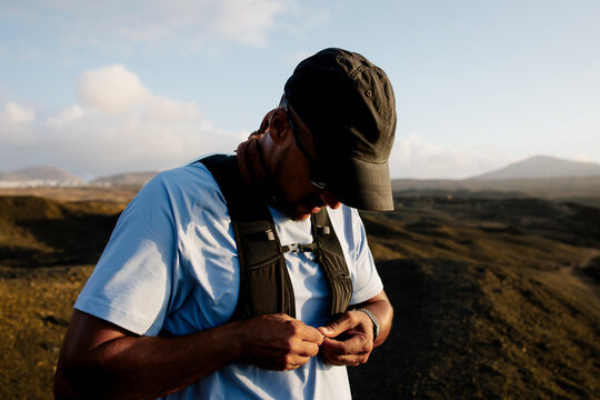 Athletic man fastening his jogging backpack to start trail running