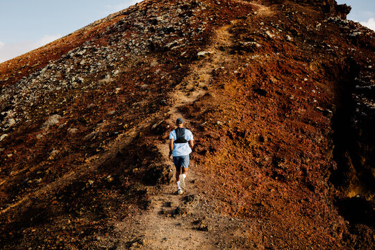 Man runs uphill on a singletrack for hiking during a sunny morning