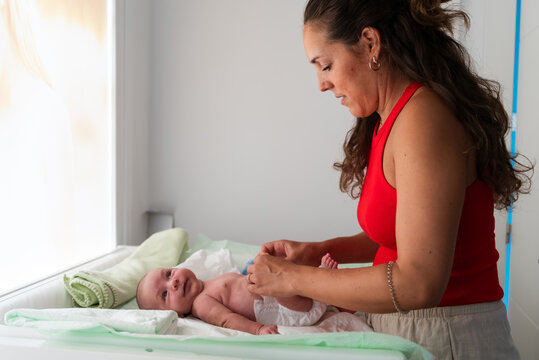Mother changing her baby on a changing table