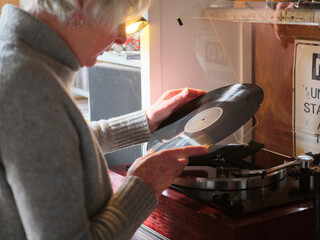 Elderly trans woman playing vinyl records on a turntable at home