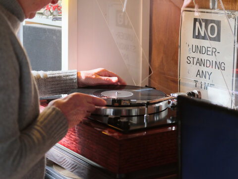Elderly trans woman placing vinyl record onto vintage turntable