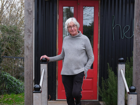 Portrait of older trans woman on steps of her home