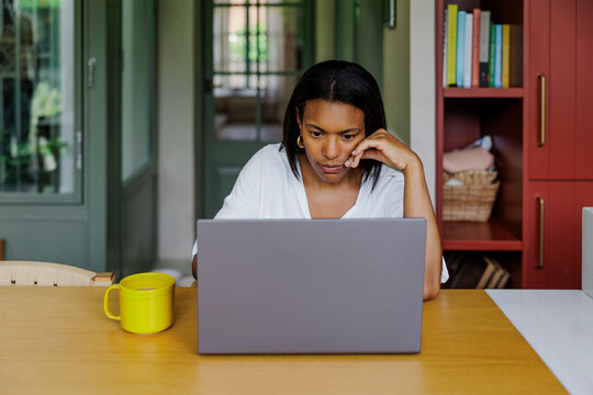 Focused woman working from home having issues with laptop