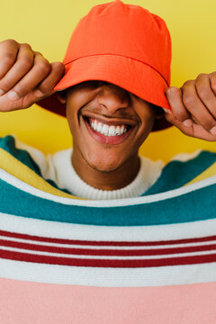 Man wearing colorful sweater pulling down bucket hat