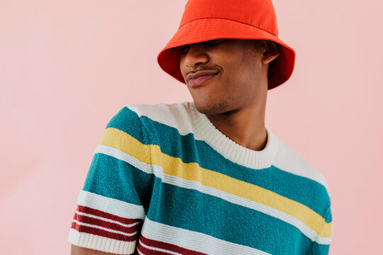 Man wearing colorful clothes and red bucket hat posing on studio