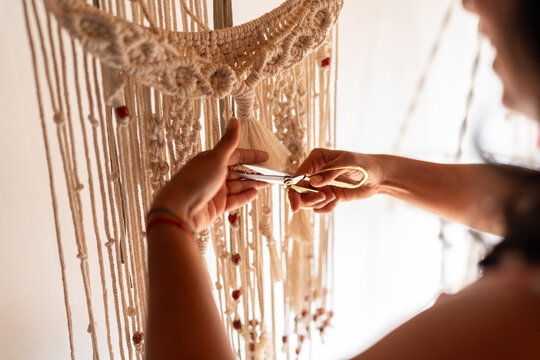 Artist cutting macrame textile wall hanging with scissors