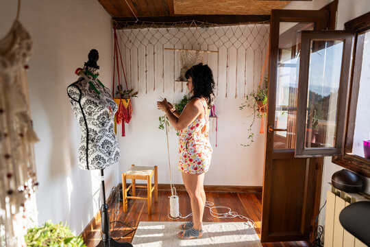 Textile artist designing macrame wall hanging in her home studio