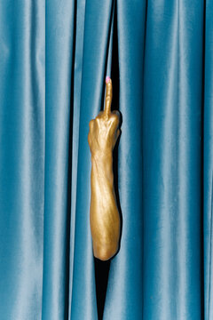 Golden Arm Giving Middle Finger Behind Blue Curtain