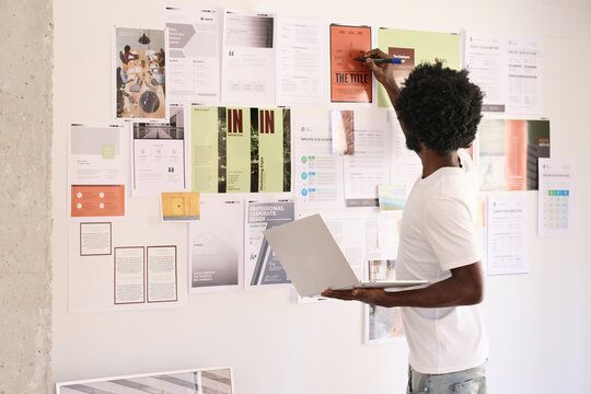 afro worker writing some correction on a work in progress projec