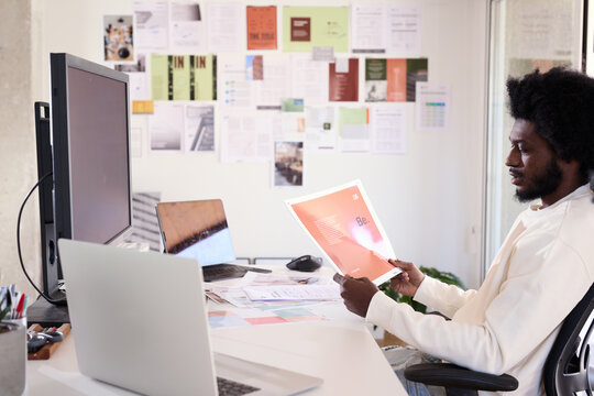 Designer Evaluating Graphic Print. Black businessman reviewing p
